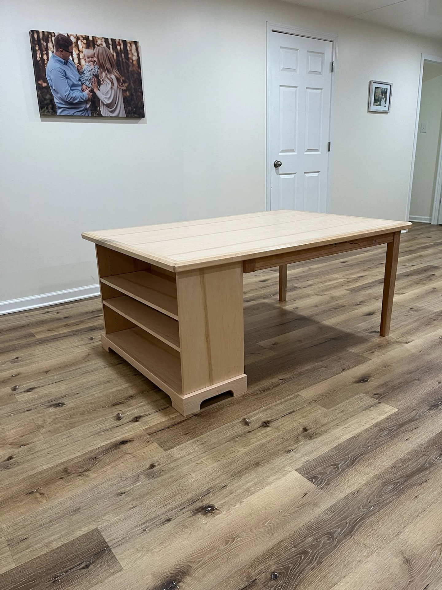 Large light maple craft table with open shelving built into one leg base