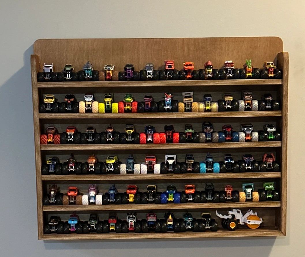 Large stained plywood wall shelf with six rows filled with toy monster trucks